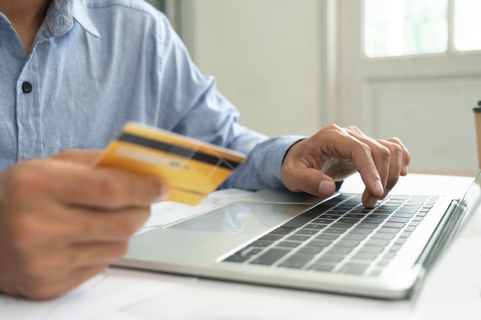 Businessman using laptop and credit card for e-commerce business at home.